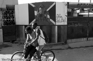 Residents of St. Marc cycle past painting of late Jamaican reggae superstar, Bob Marley on the streets on St. Marc on February 22, 2004. 